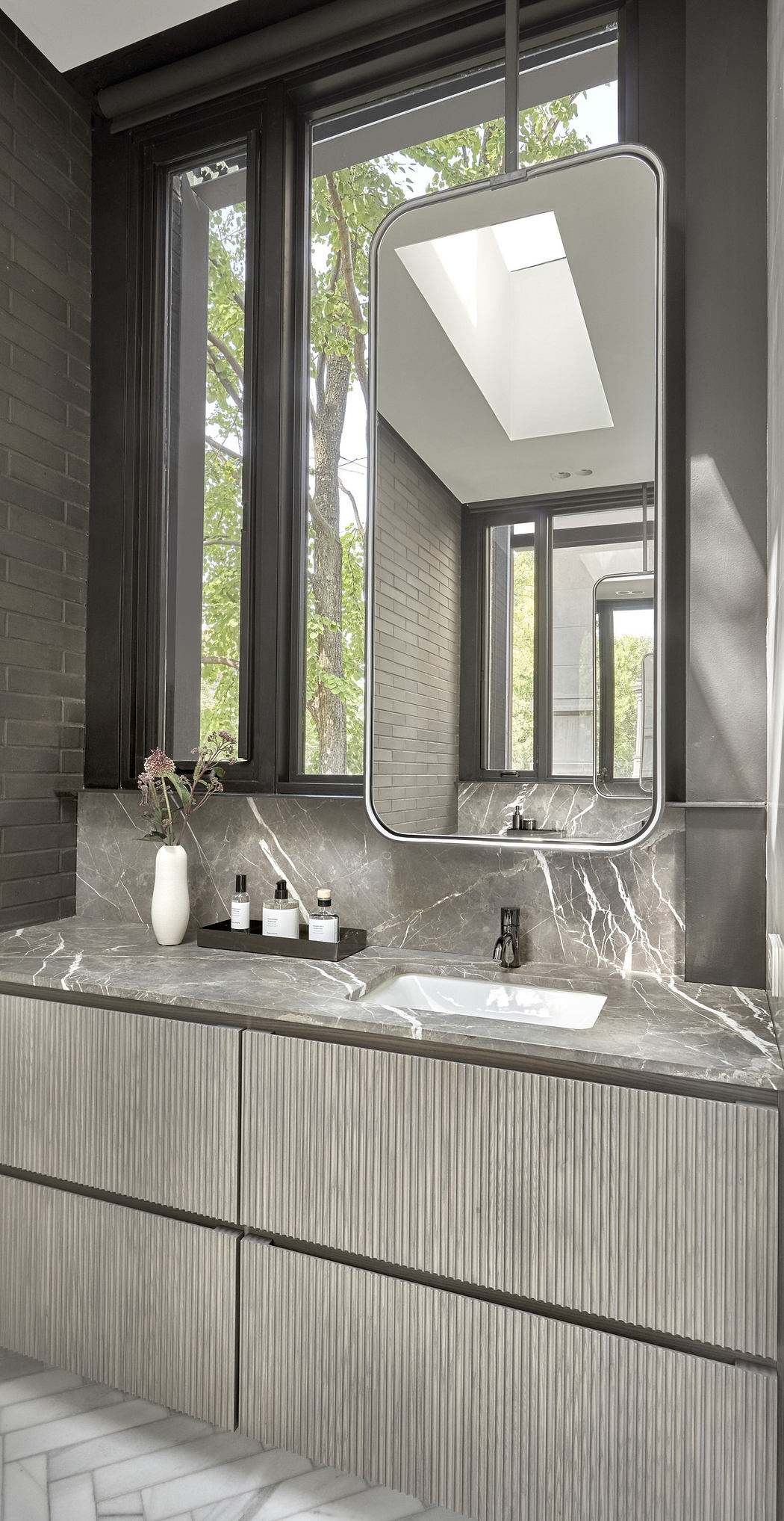 Modern bathroom with marble countertop, large mirror, and tall windows.