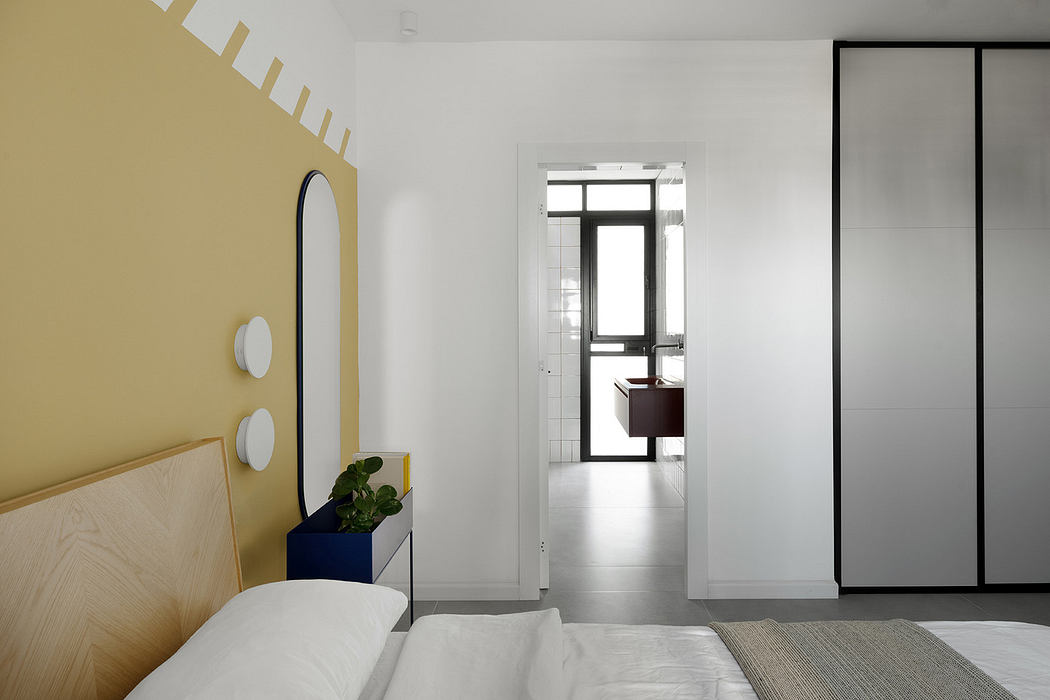 Modern bedroom interior with white bedding and contrasting yellow accent wall.