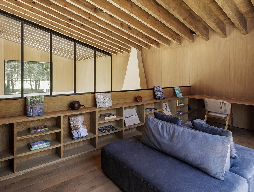 Modern wooden interior with bookshelves, sofa, and large windows.
