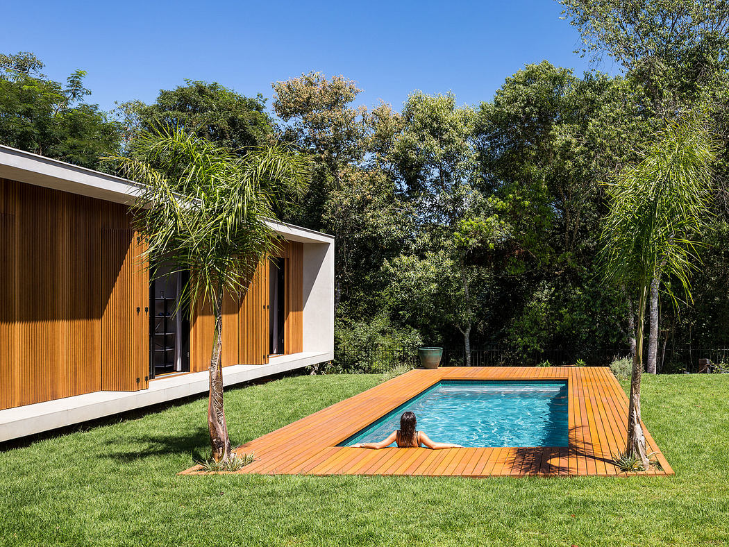 Modern house with wooden facade and pool deck surrounded by greenery.