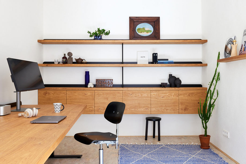 Modern home office with wooden desk, shelving, and minimalist decor.