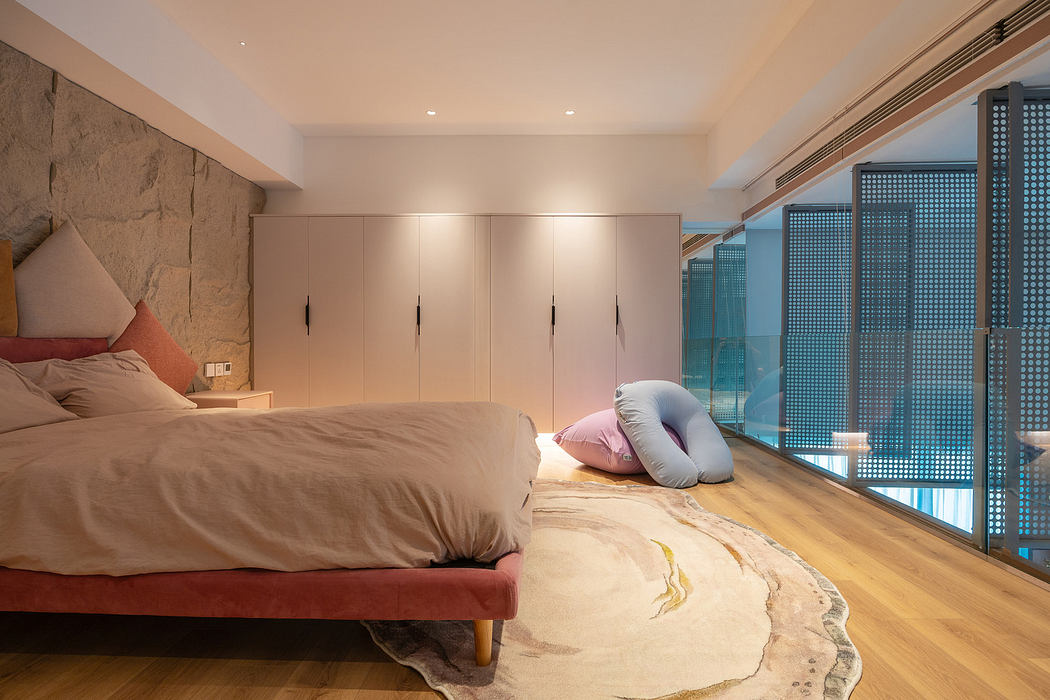 Modern minimalist bedroom with large bed, stone accent wall, and floor-to-ceiling