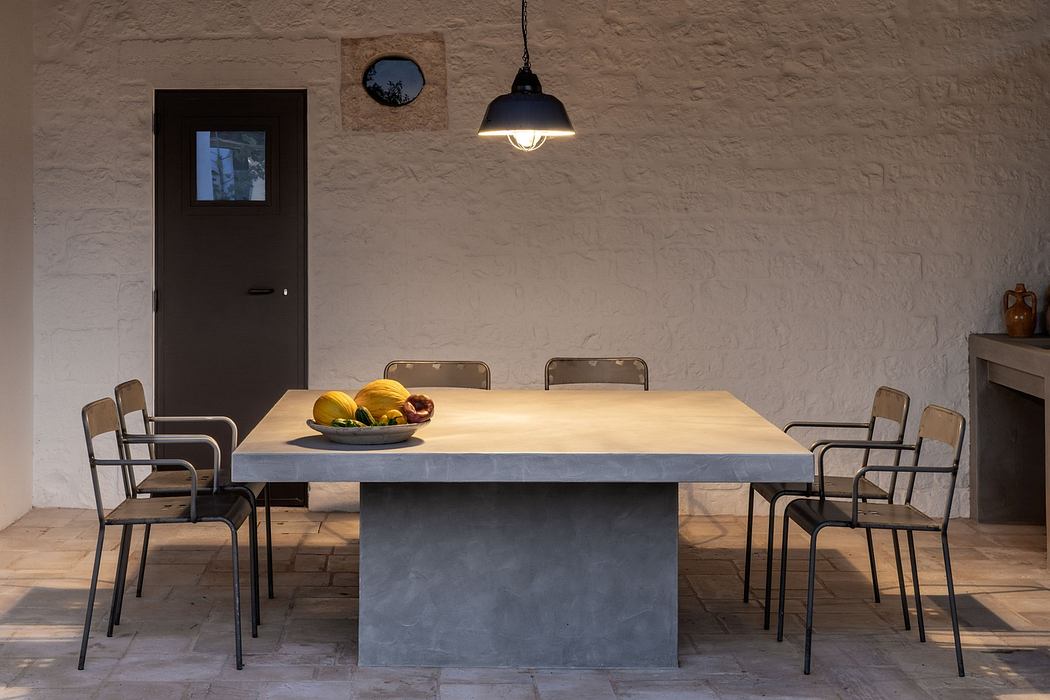 Minimalist dining room with concrete table, metal chairs, and pendant light.