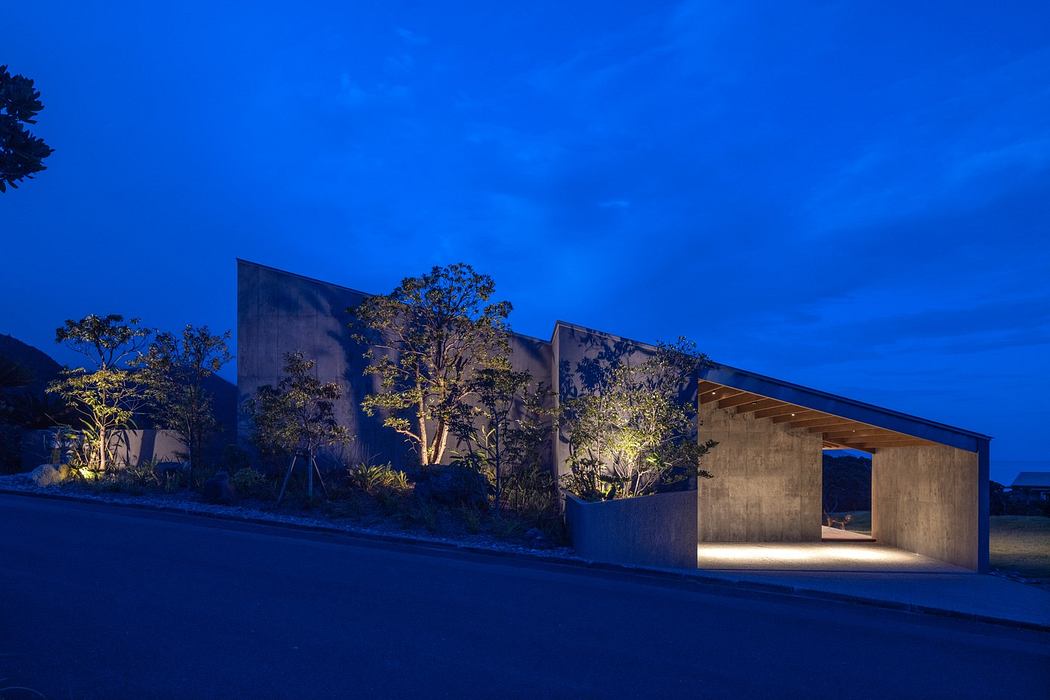Modern building at twilight with illuminated interior and trees.