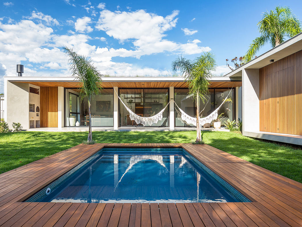 Modern backyard with a rectangular pool, wooden deck, hammocks, and minimalistic