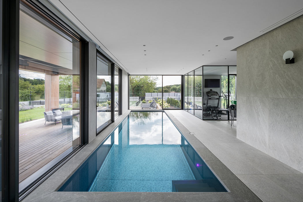 Modern indoor pool with large windows, sleek design, and outdoor view.