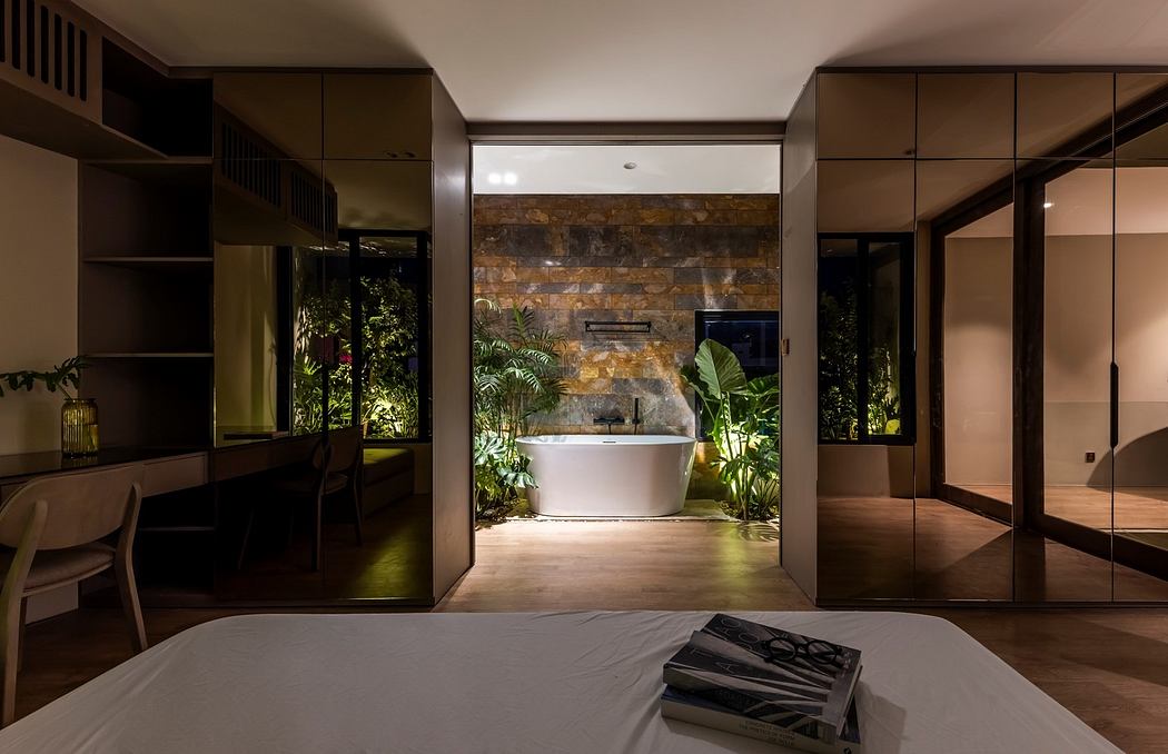 Modern bedroom with reflective wardrobes and central bathtub surrounded by indoor plants.