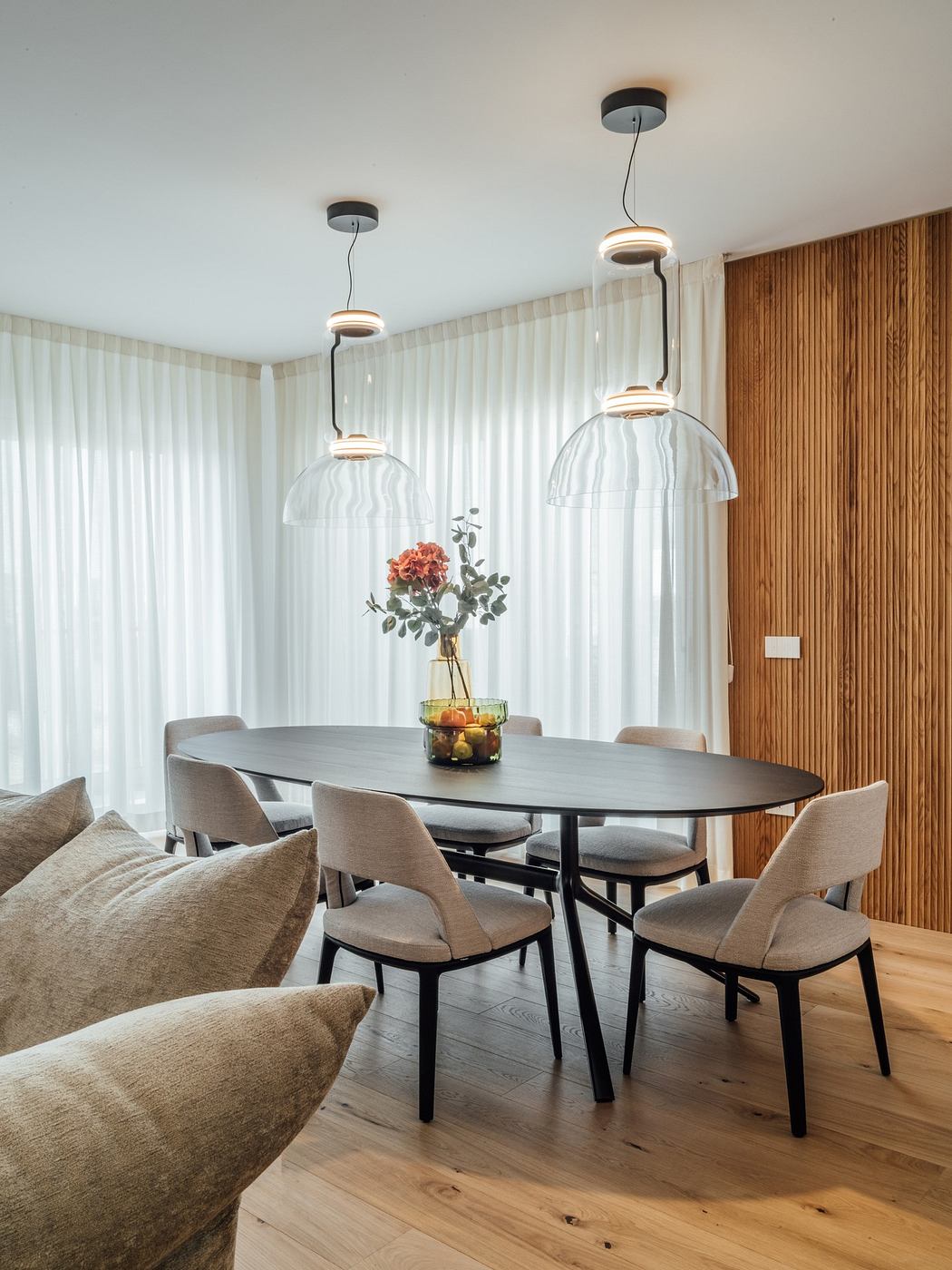 Modern dining room with wooden paneling and elegant pendant lights.