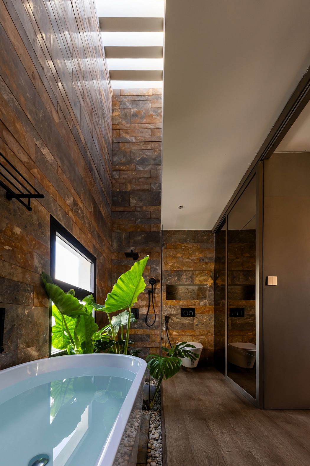 Modern bathroom with a freestanding tub, wood-paneled walls, and sk