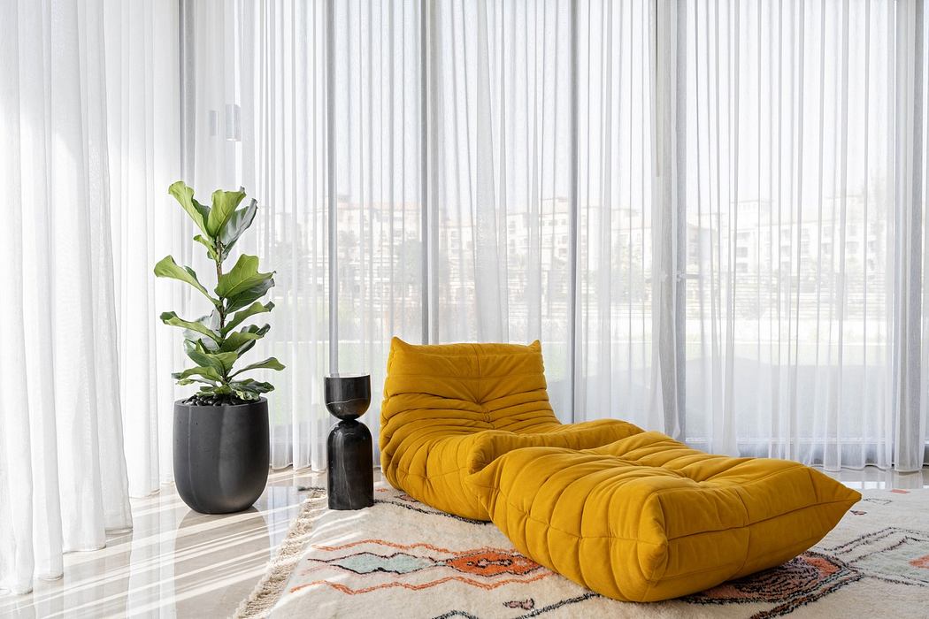 Bright room with sheer curtains, yellow lounge chair, and potted plant.