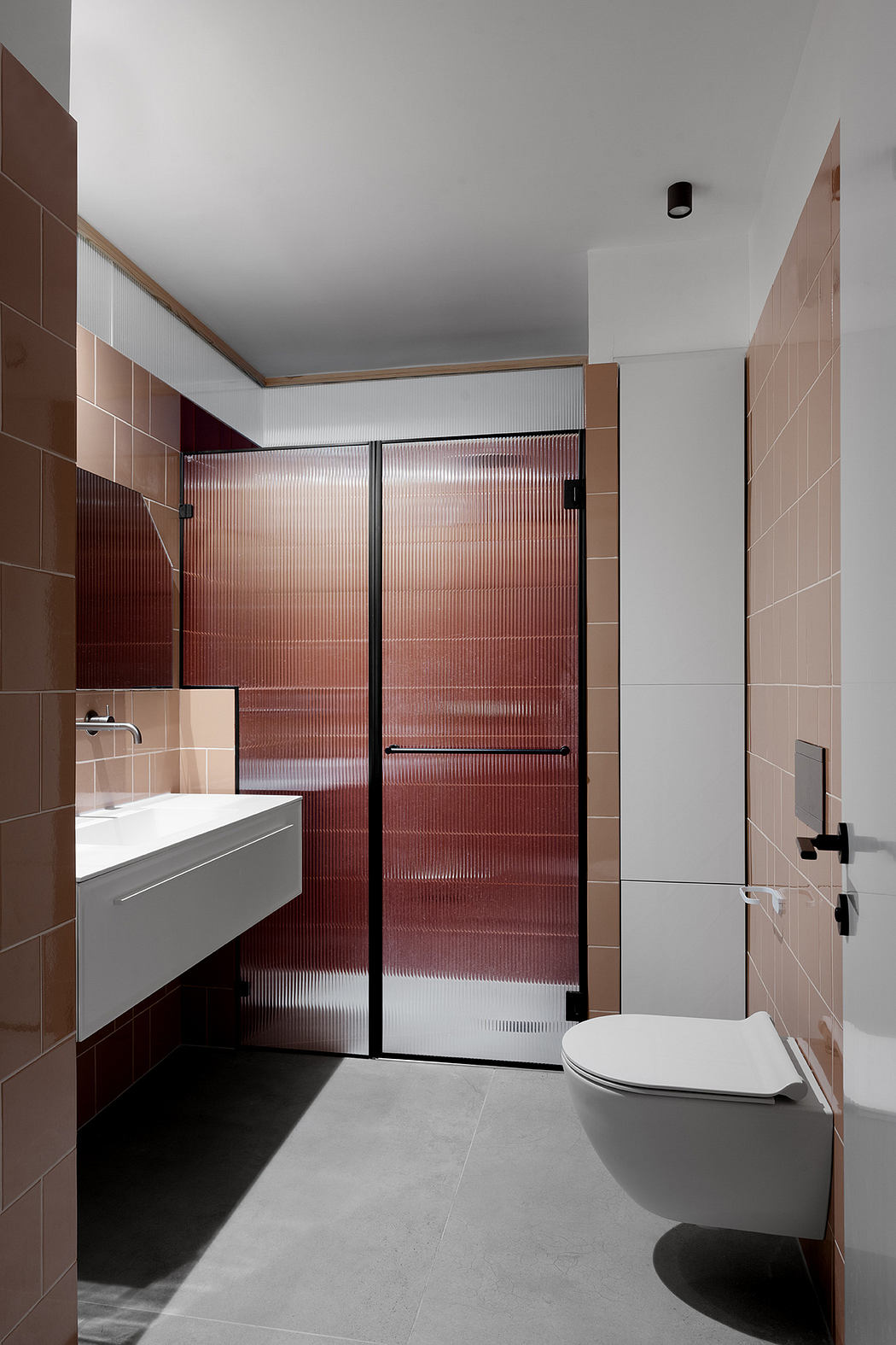 Modern bathroom with terracotta tiles, white fixtures, and glass shower.