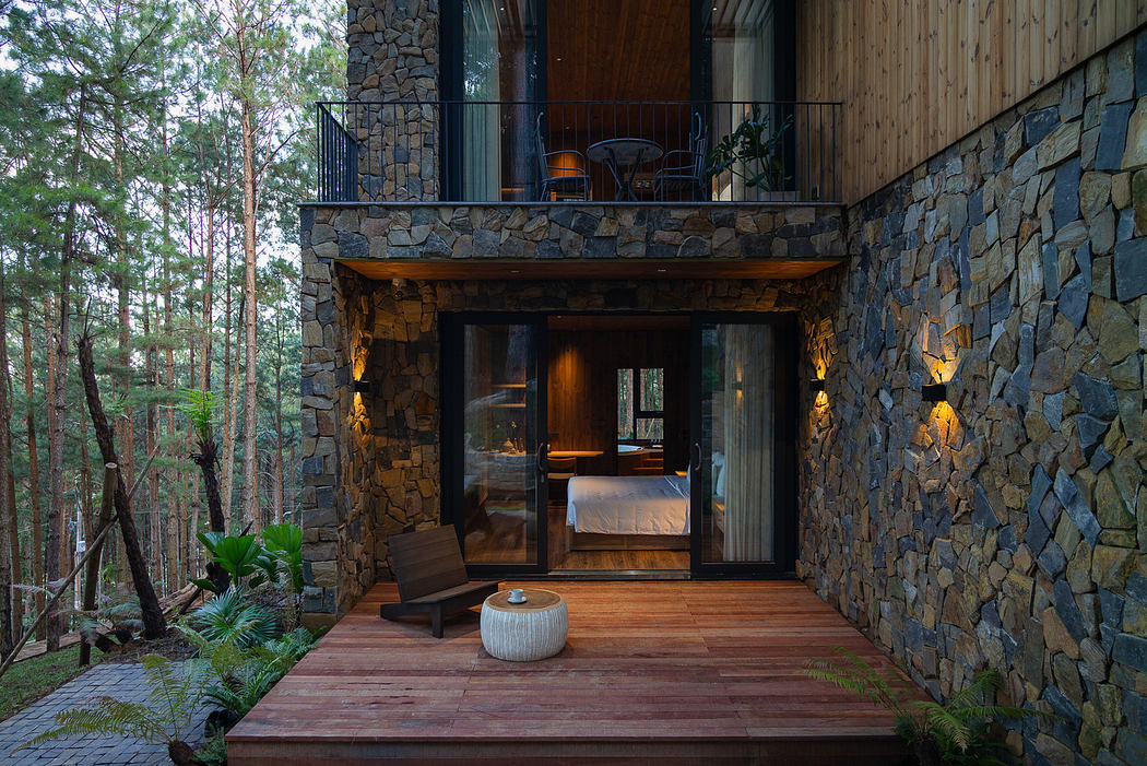 Wooden terrace of a stone and wood house surrounded by forest at dusk.