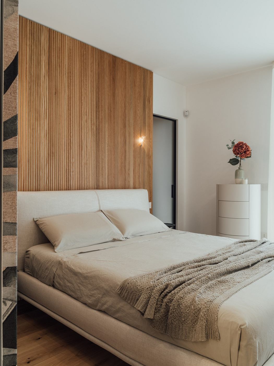 Modern bedroom with wooden headboard and neutral bedding.