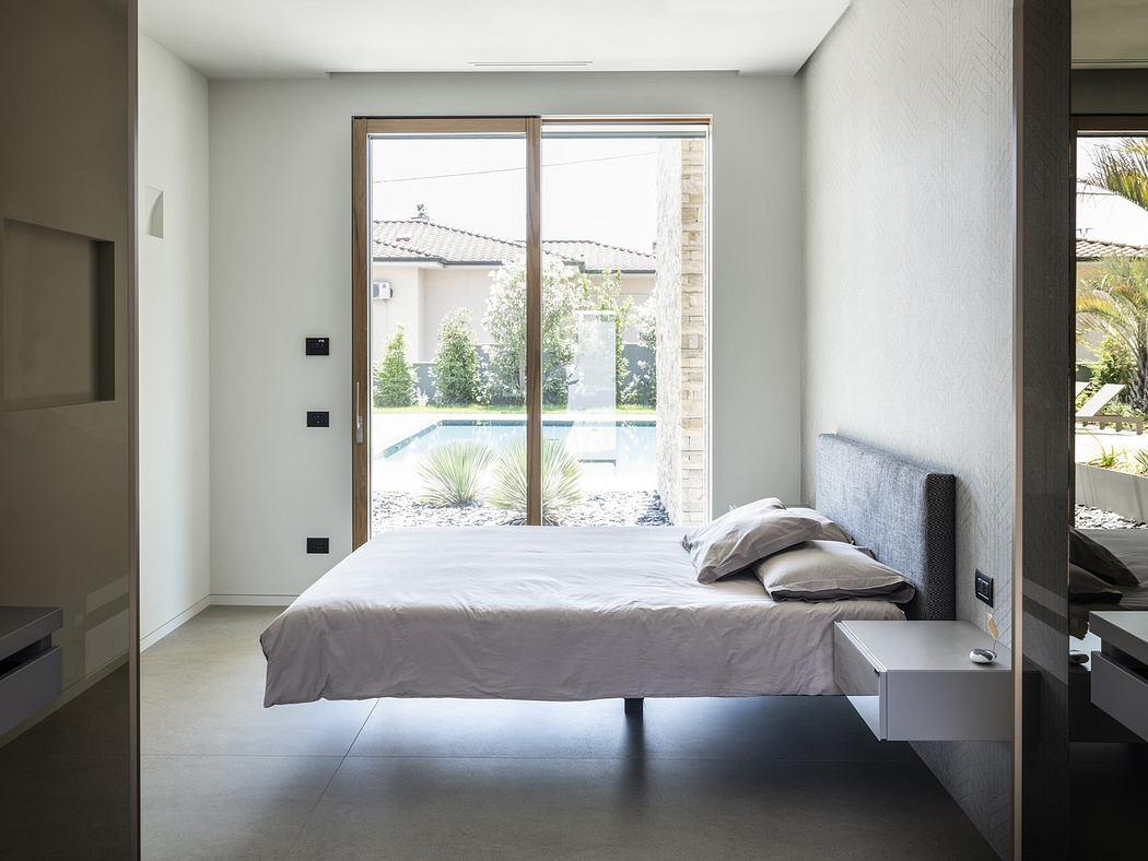 Modern minimalist bedroom with large window overlooking pool.