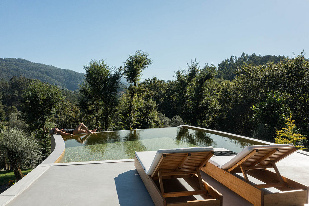 Modern infinity pool with loungers overlooking hills.
