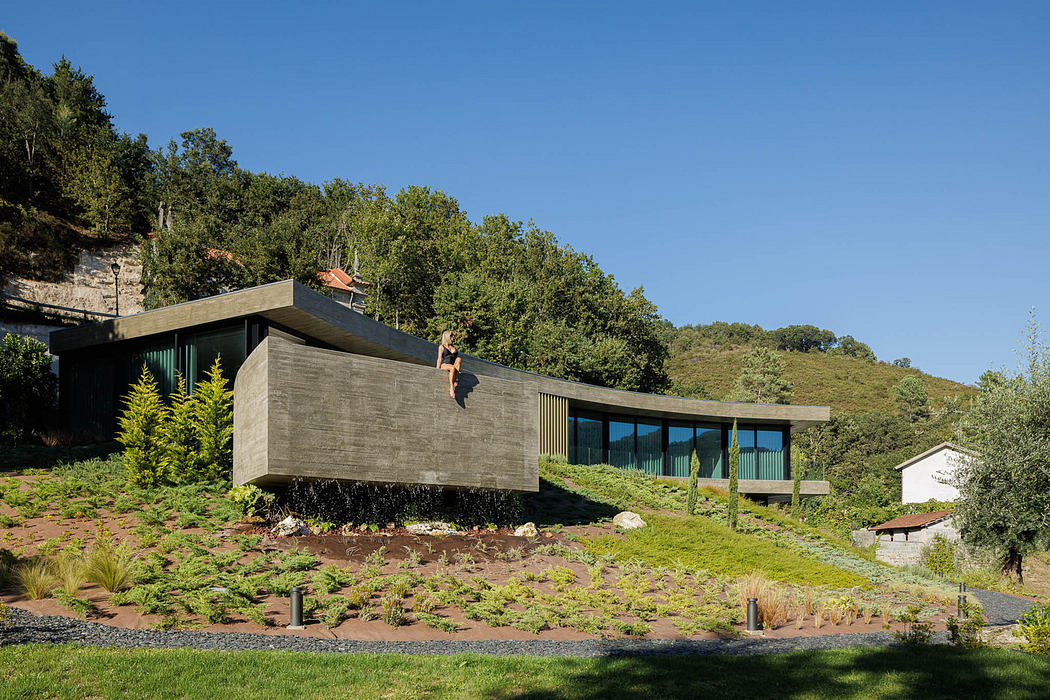 Modern hillside house with green roof and extensive glass facades.