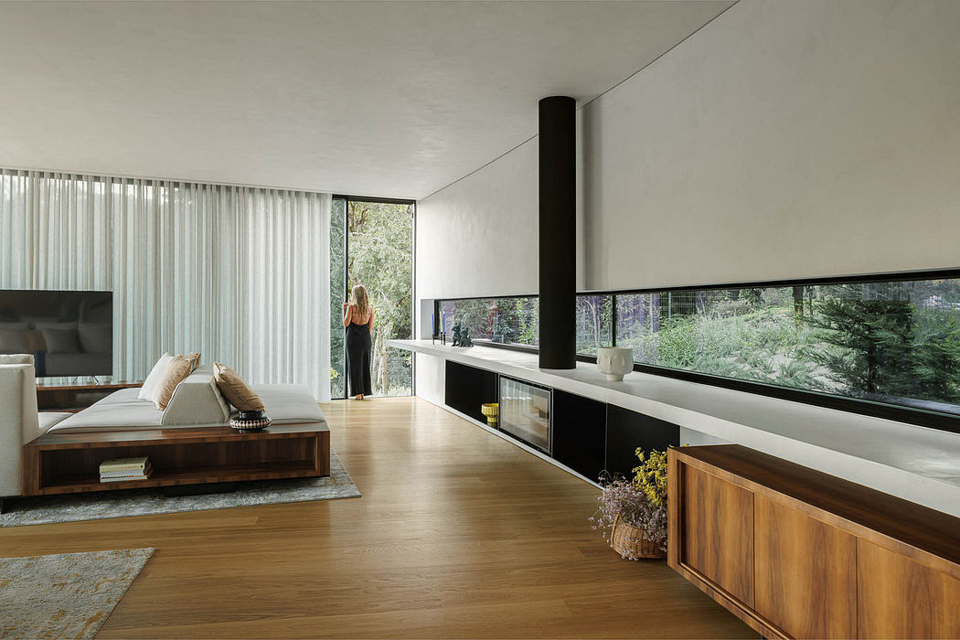 Modern living room with large windows, wooden floors, and minimalist furniture.