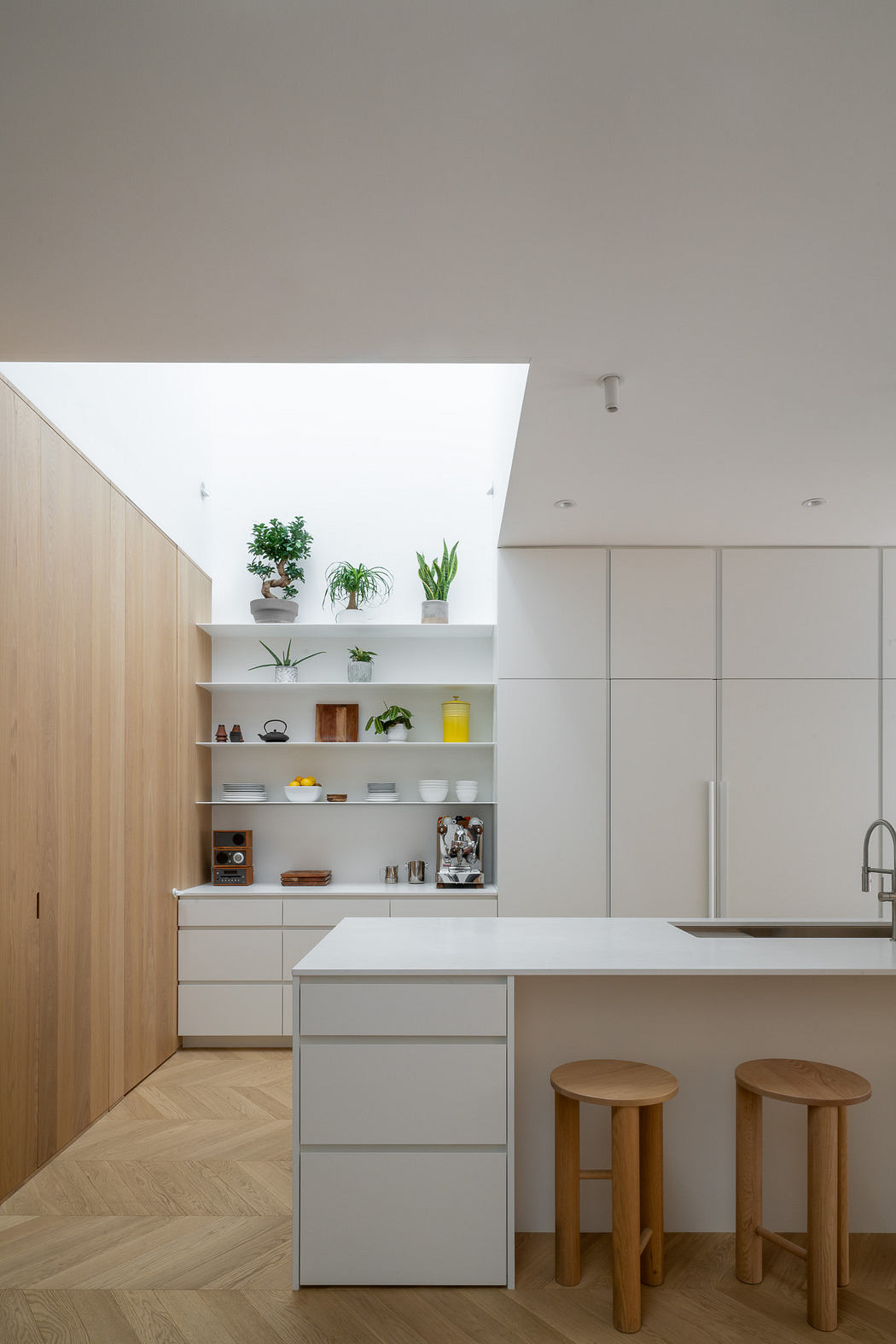 Modern kitchen with white cabinets, skylight, and wooden accents.