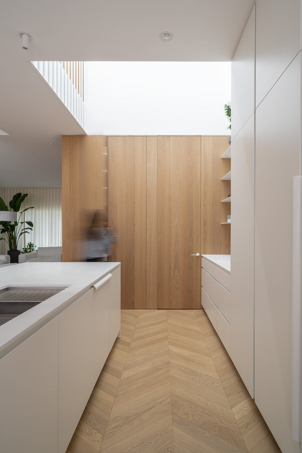 Modern kitchen with white cabinets, wooden accents, and a skylight.