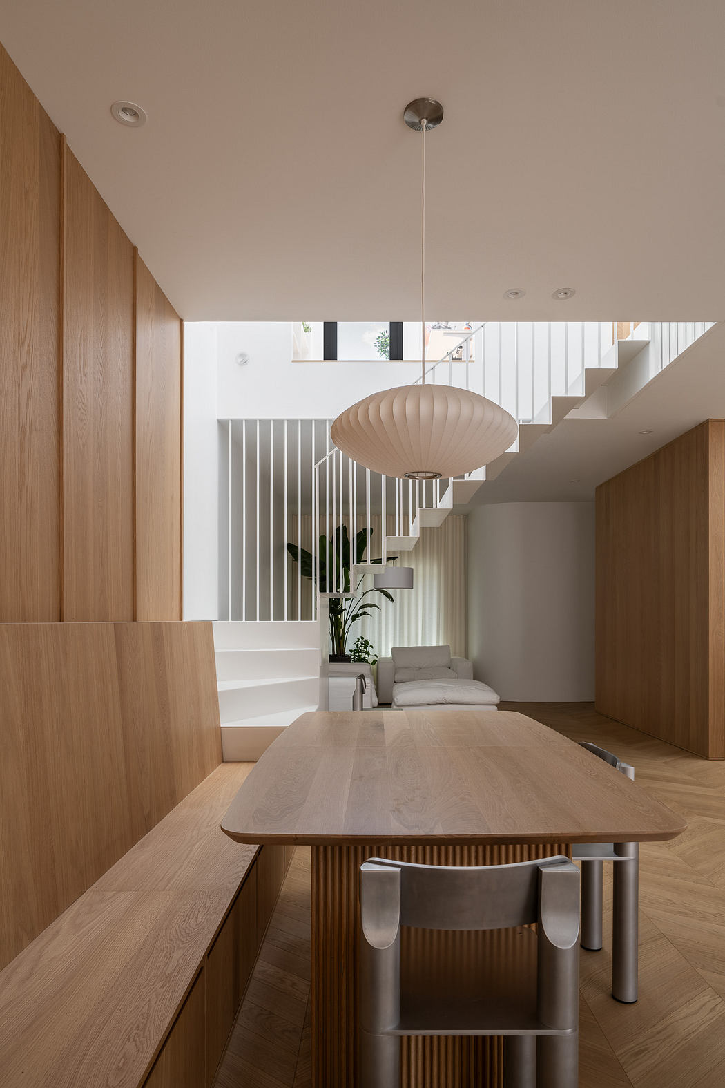 Modern minimalist interior with wooden furniture and white staircase.