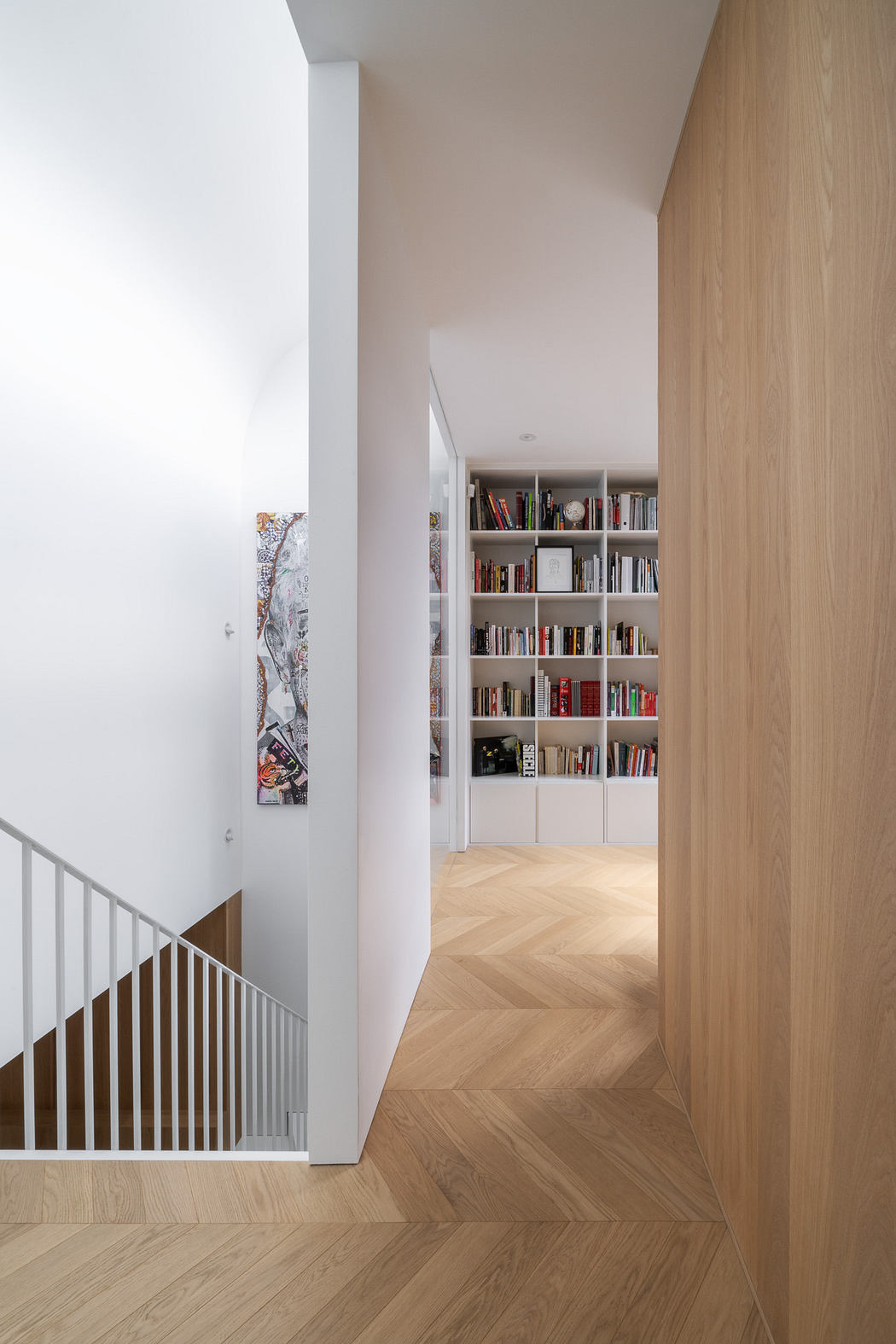 Modern hallway with herringbone floor and built-in bookshelf.