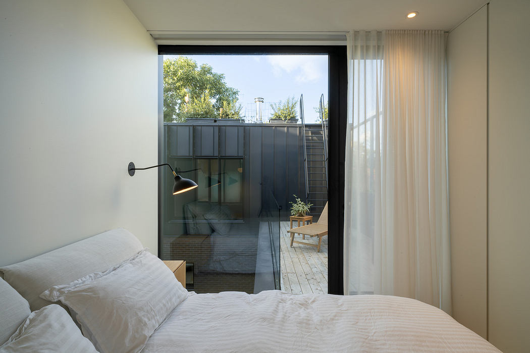 Modern bedroom with large window overlooking a patio.