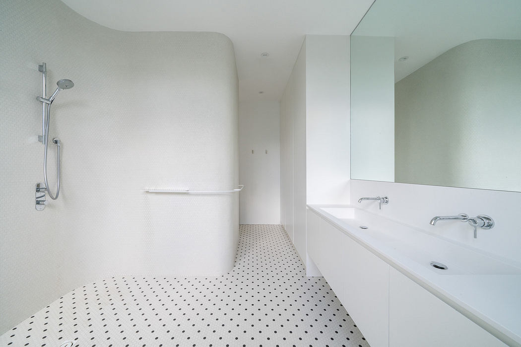 Minimalist white bathroom with curved walls and a dotted floor design.