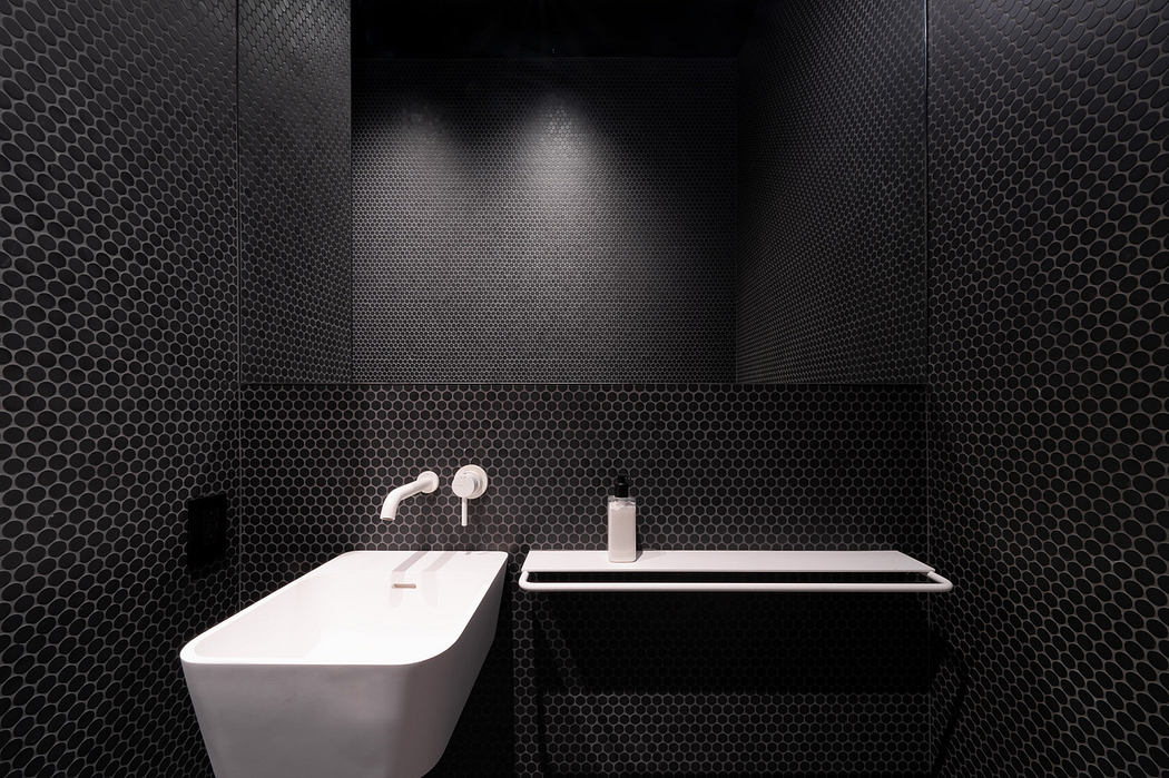 Modern bathroom with black hexagonal tiles and white fixtures.