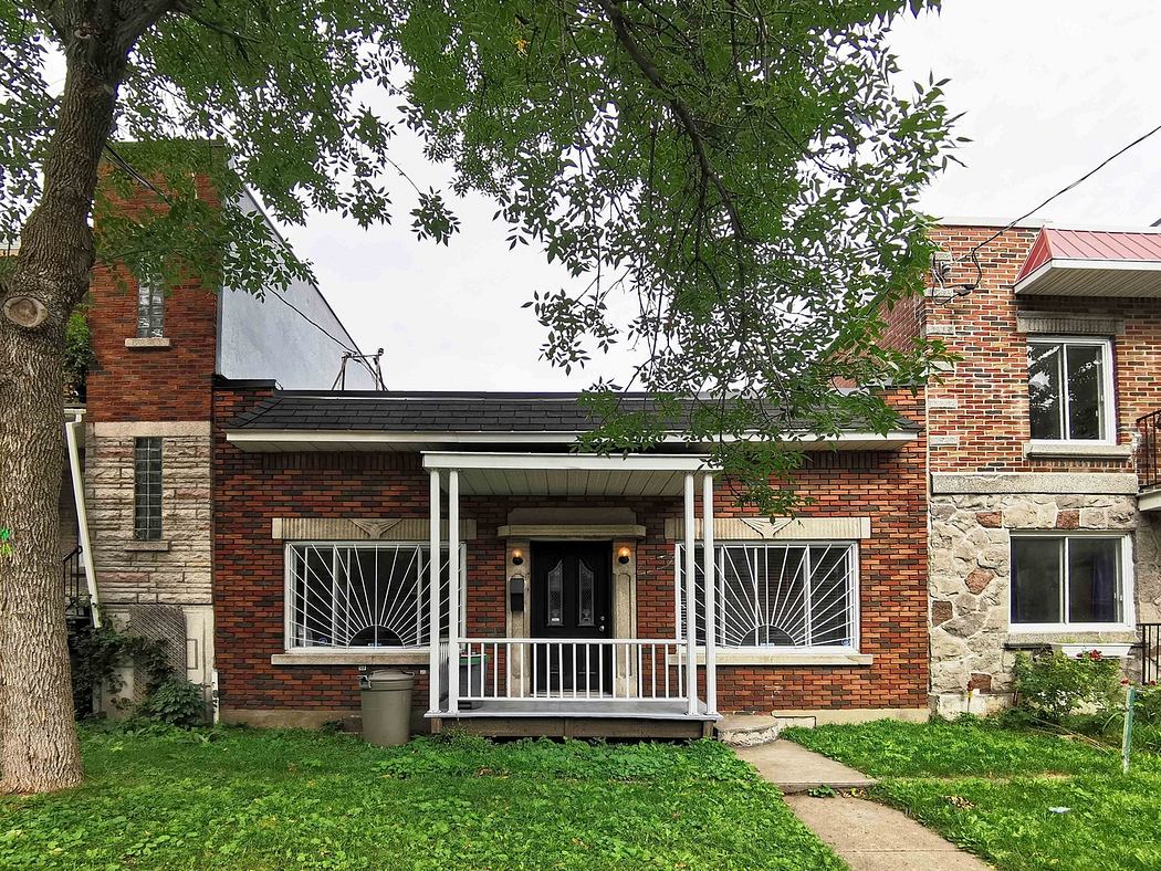 Red brick house with white porch and green lawn.