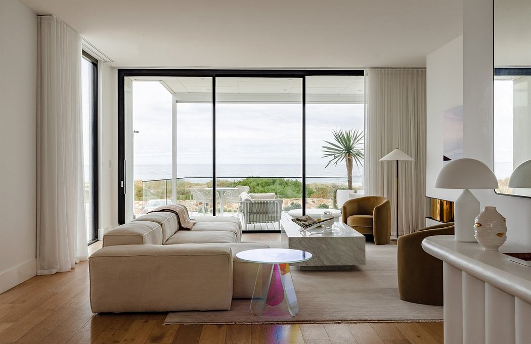 Modern living room with large windows, minimalistic furniture, and an ocean view.