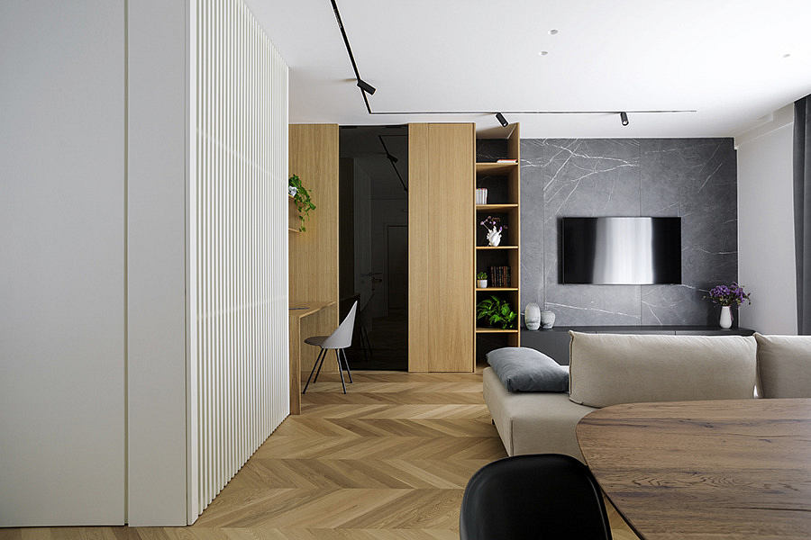 Modern living room with a herringbone wood floor, gray sofa, and marble
