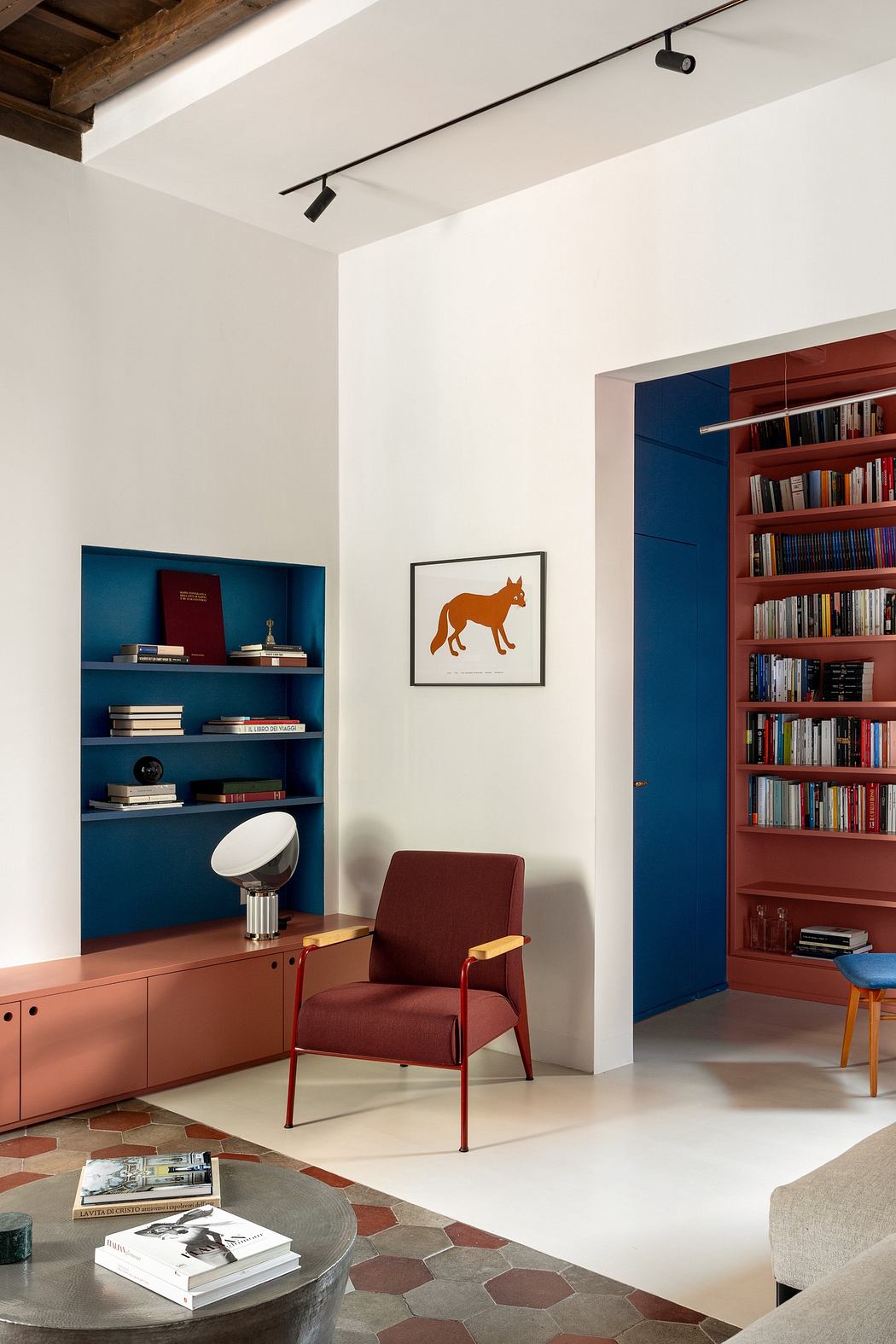 Modern living room with blue bookshelf, red chair, and terracotta accents