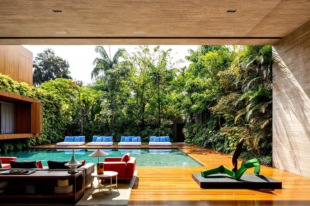 Modern living room opening onto a pool with lush greenery in the background.
