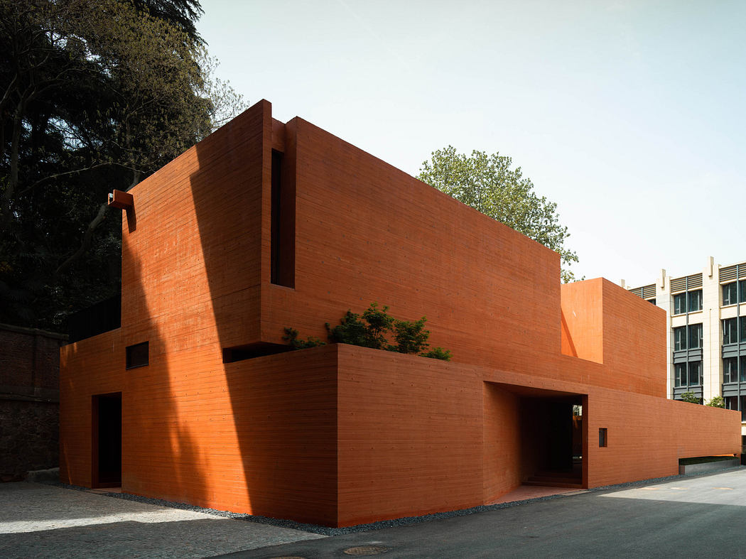 Modern terracotta brick building with geometric design and shadows.