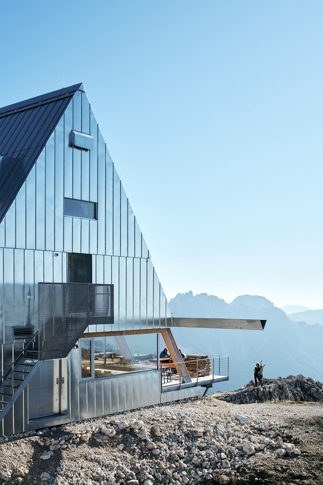 Futuristic alpine hut with large glass facade on mountain peak.
