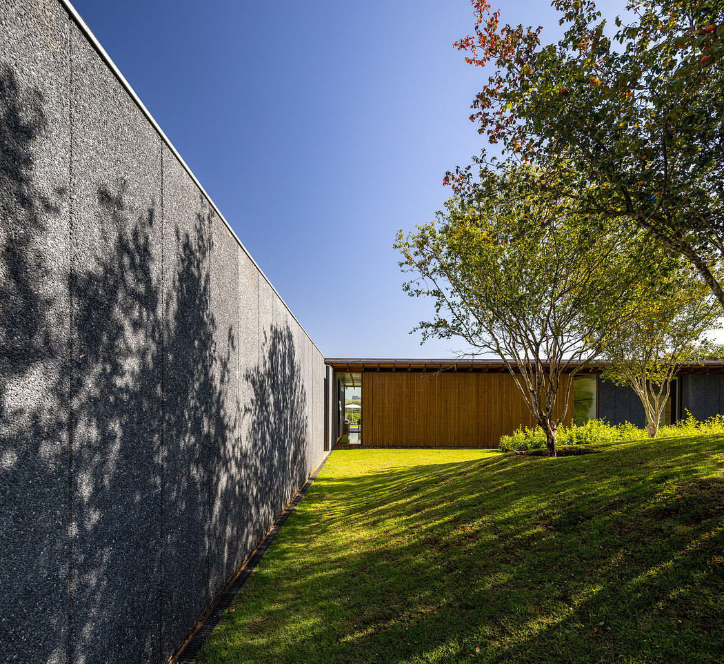 Linear building with textured wall, adjacent to a garden.