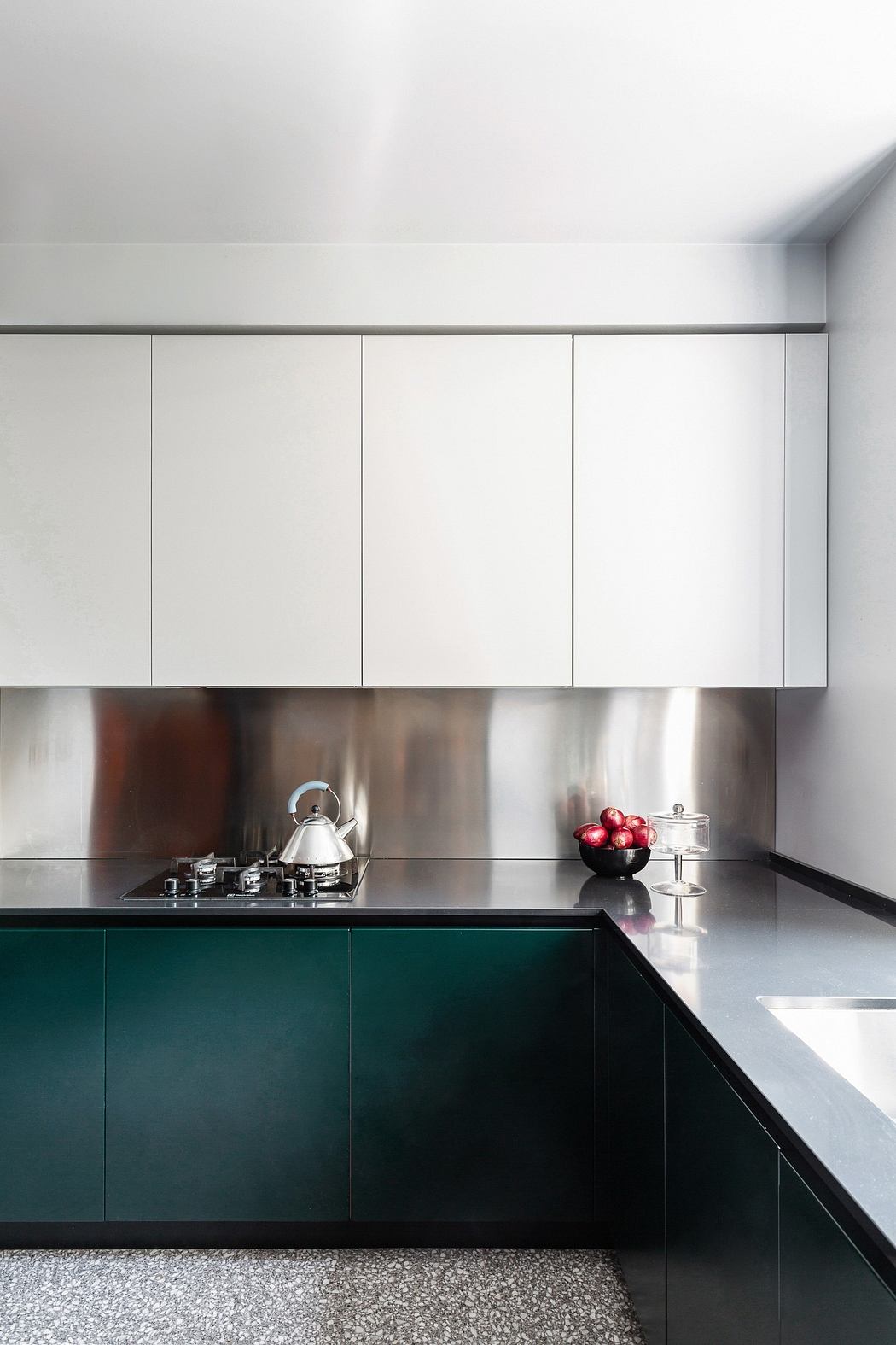 Modern kitchen with white cabinets, stainless steel backsplash, and dark countertop.