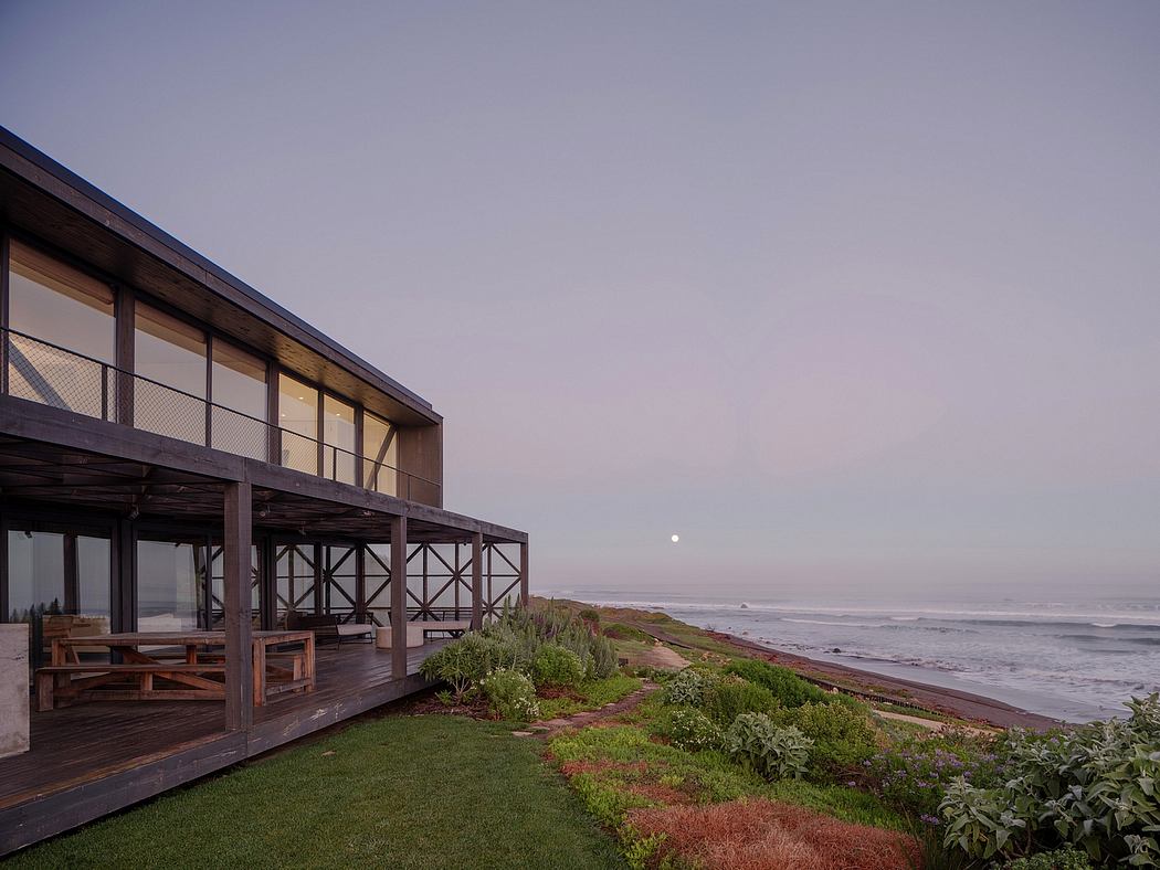 Contemporary beach house with large windows at dusk.
