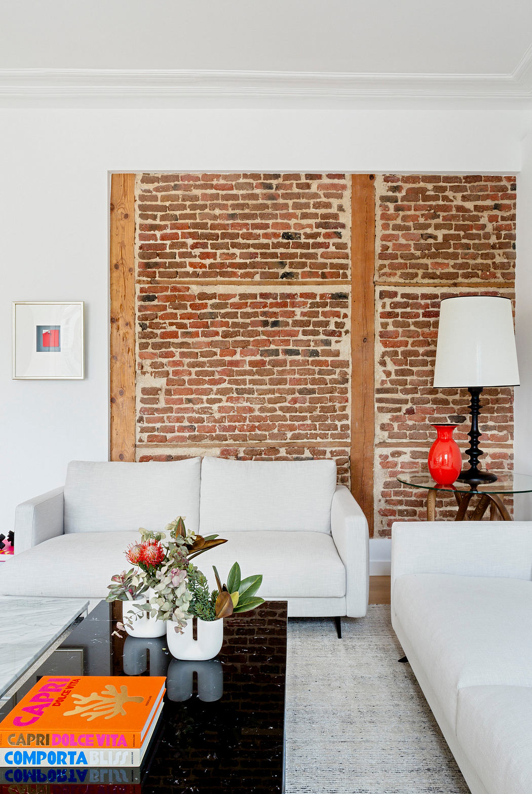 Modern living room with exposed brick wall and white sofas.