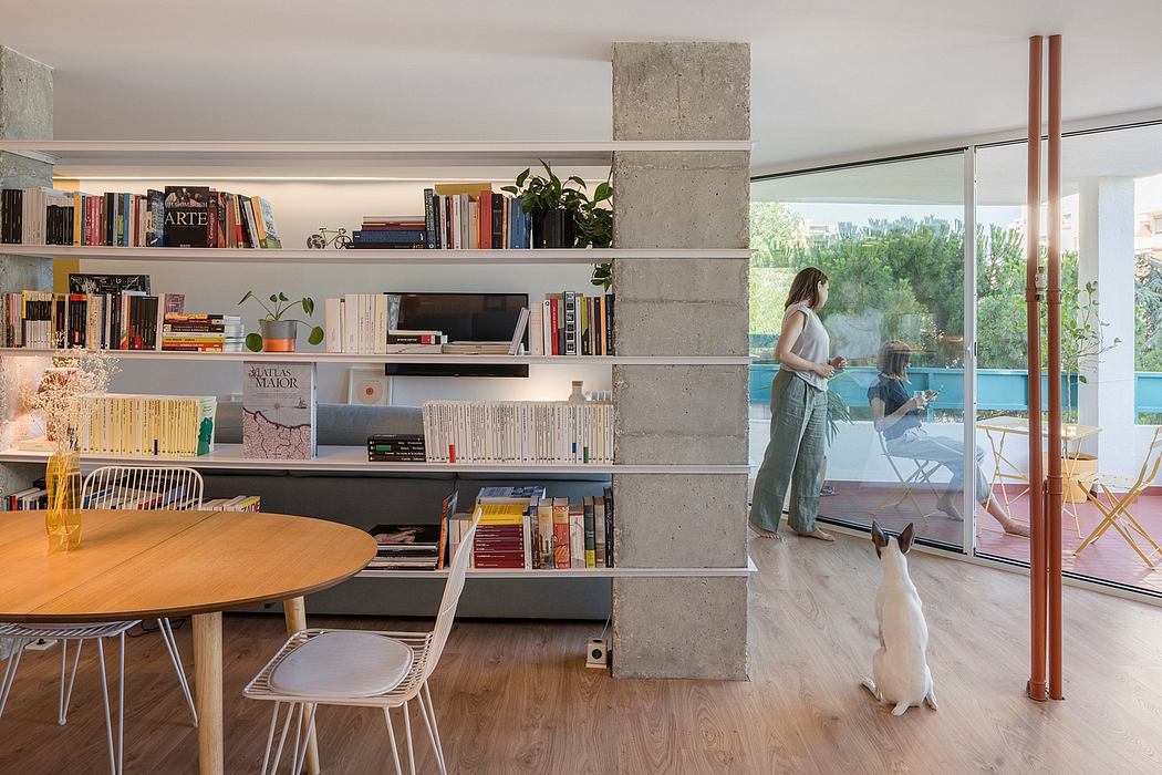 Modern interior with bookshelves, a woman by glass door, and a dog