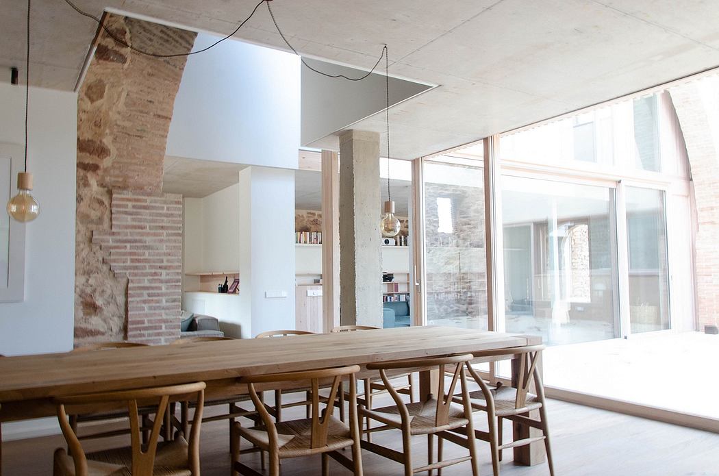 Modern dining room with wooden table, chairs, and exposed brick.