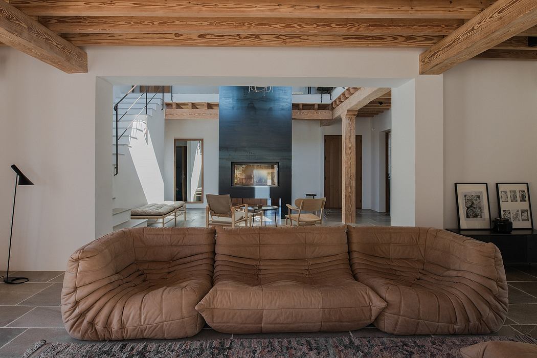 Modern room with exposed beams, plush sofa, and dining area in the background.