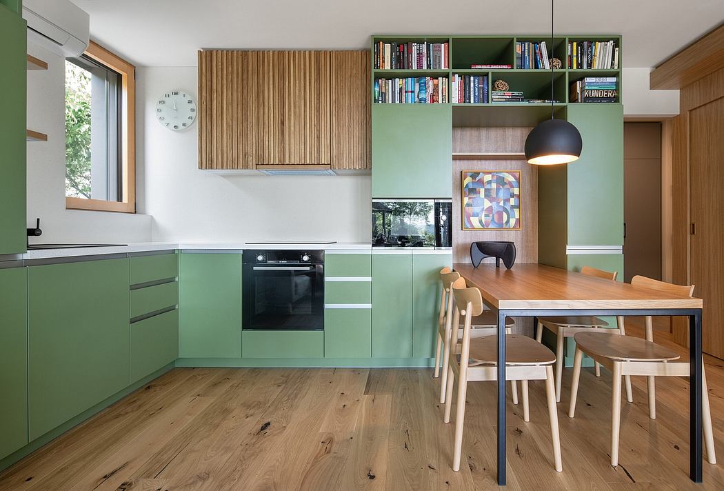 Contemporary green kitchen with wooden table and shelving.