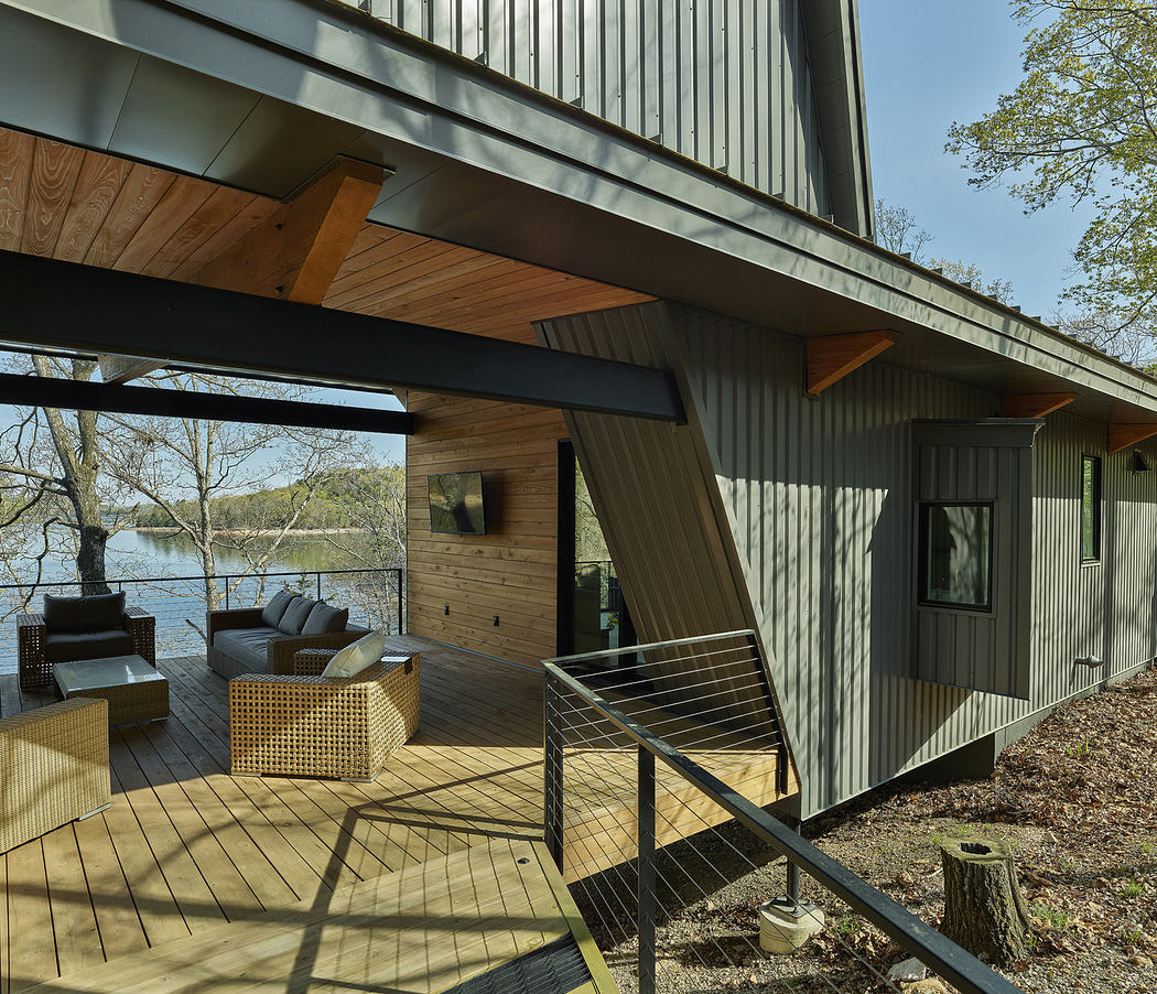 Exterior view of a modern house with a deck overlooking a lake.