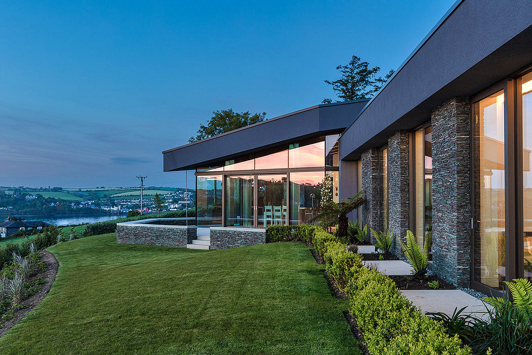Contemporary house with large windows and stone facade at dusk.