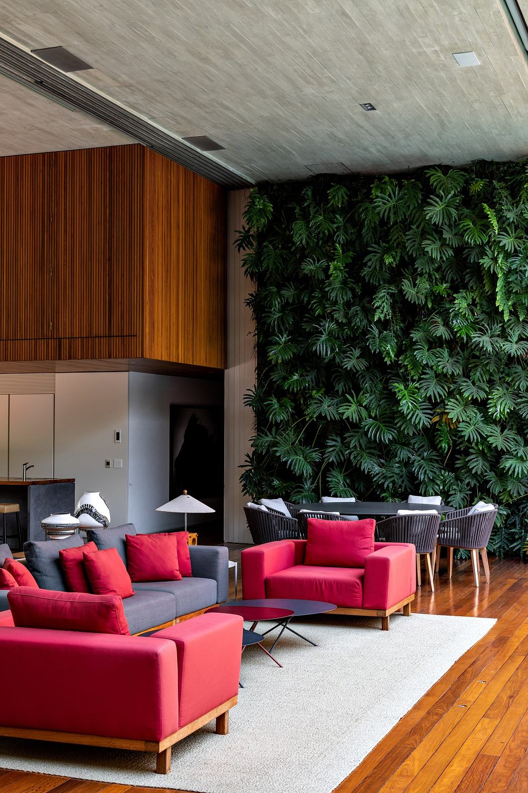 Contemporary living space with vibrant red sofas and a lush green living wall.