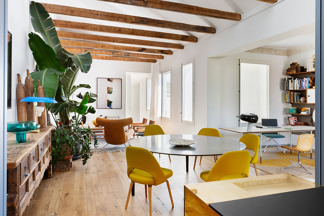 Modern room with wooden beams, a dining table with yellow chairs, and plants.
