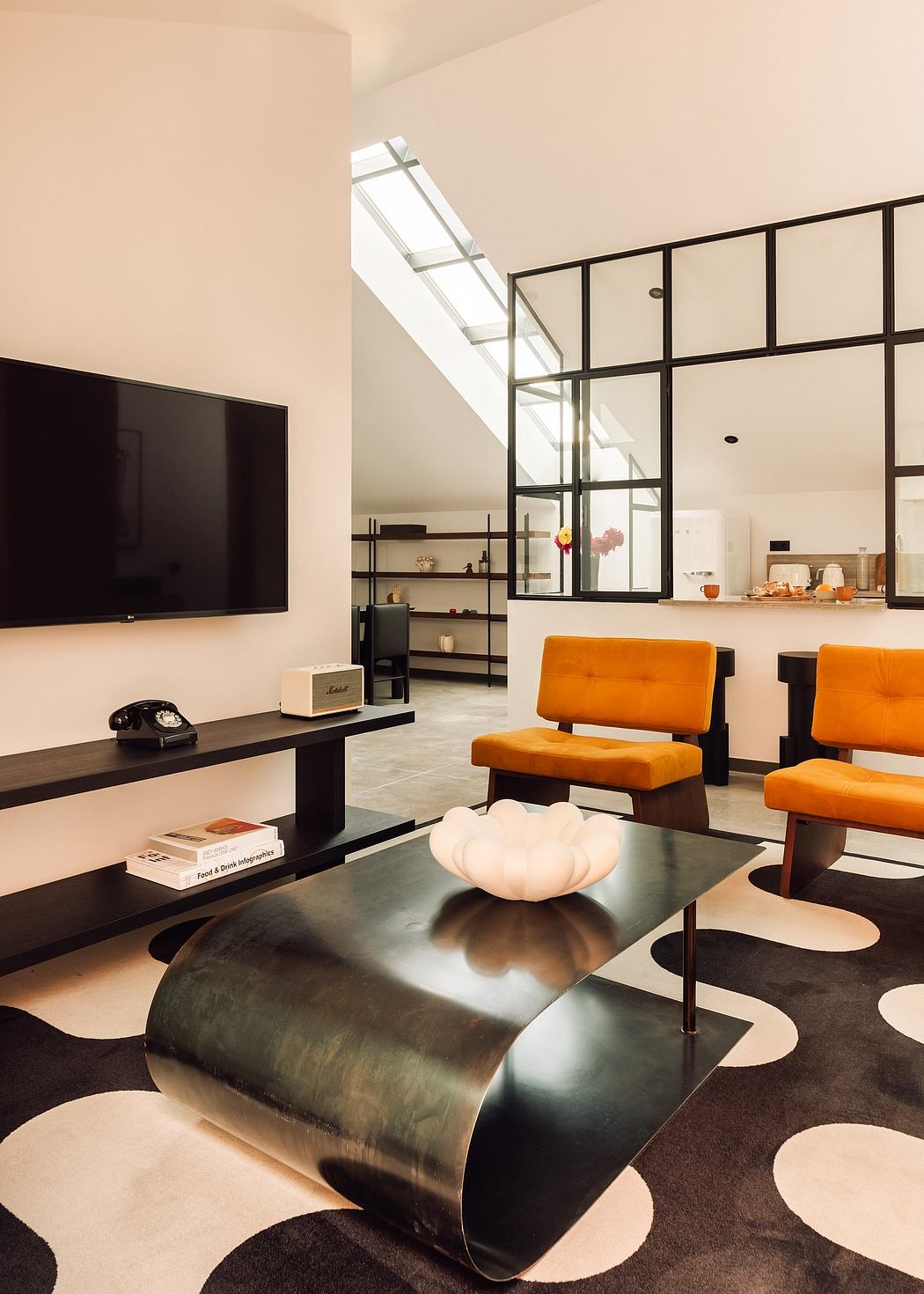 Modern living room with skylight, black-framed glass partition, and stylish