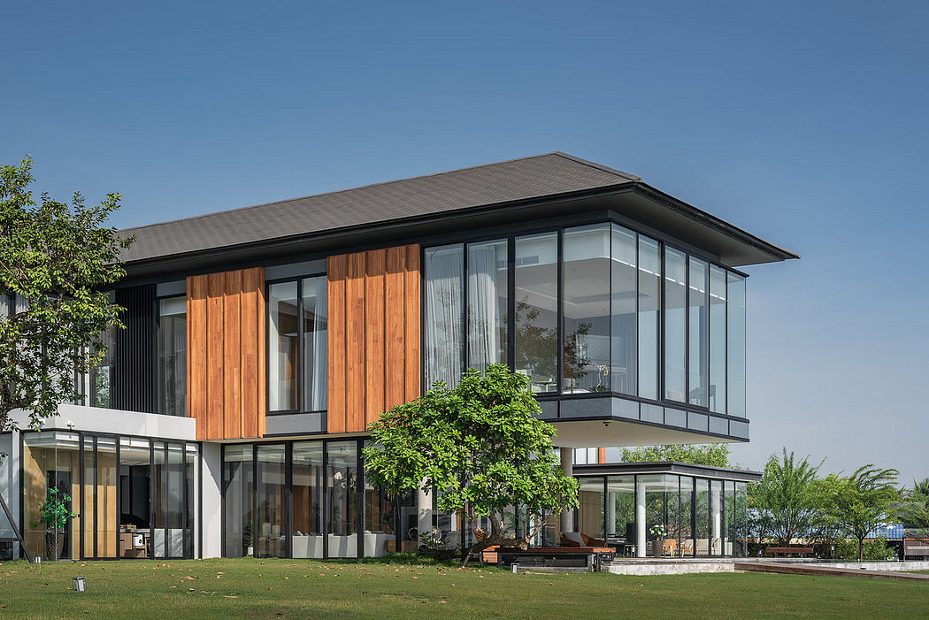 Modern two-story house with large glass windows and wooden panels.