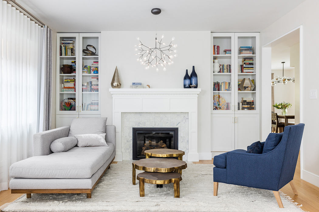 Modern living room with white built-in shelves, a fireplace, and blue armchair